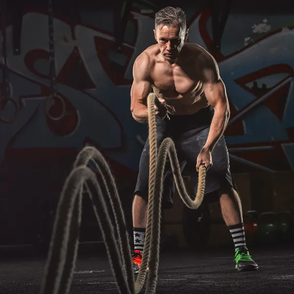 senhor de meia idade com o corpo trincado realizando exercícios com cordas